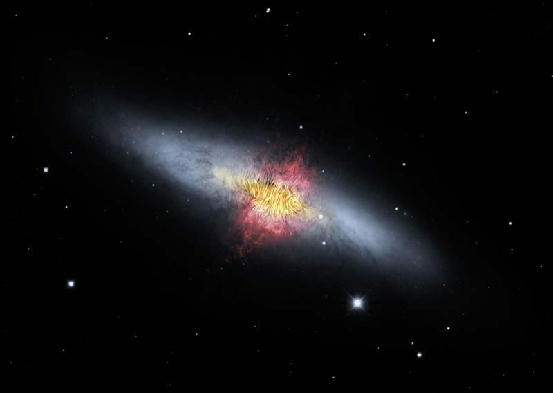 En esta imagen se pueden observar las líneas del campo magnético de la Galaxia del Cigarro (también llamada M82). Las líneas siguen los flujos bipolares (rojo) generados por ritmos excepcionalmente altos de formación de estrellas. Crédito de la imagen: NASA/SOFIA/E. Lopez-Rodiguez; NASA/Spitzer/J. Moustakas et al