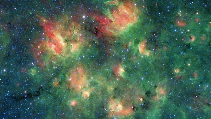 Esta nube de gas y polvo está llena de burbujas hinchadas por el viento y la radiación de jóvenes estrellas masivas. Crédito de la imagen: NASA/JPL-Caltech
