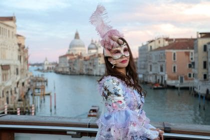 woman in venetian clothes and mask on bridge in venice