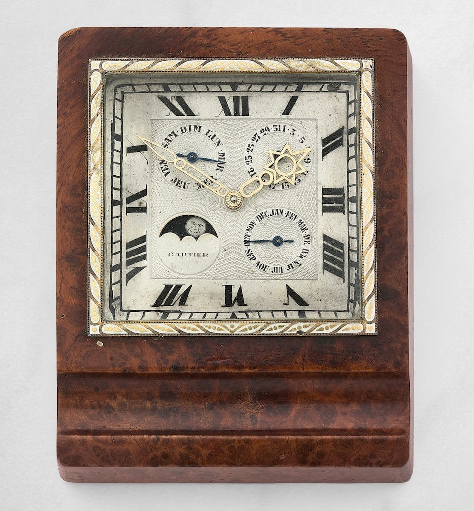 Cartier Pendulette. A mid-20th century brass and walnut burl triple calendar desk clock with moon phase indication sold for €14,662.50